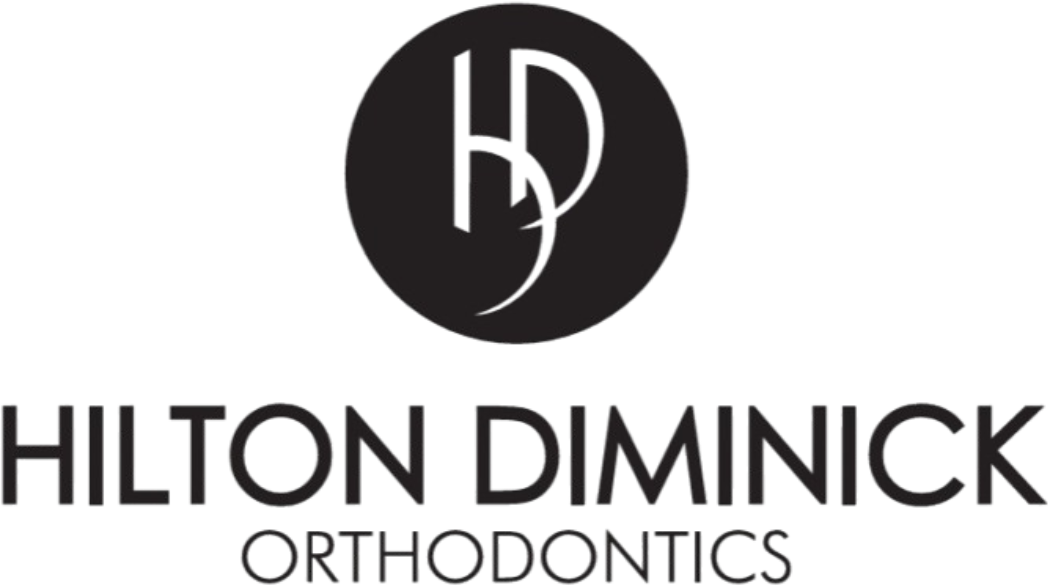 A black and white logo featuring a solid black circular emblem with stylized, overlapping letters "H" and "D" inside. Below the emblem, the words "HILTON DIMINICK" are written in a large, sans-serif uppercase font, with the word "ORTHODONTICS" in a smaller uppercase font centered underneath.