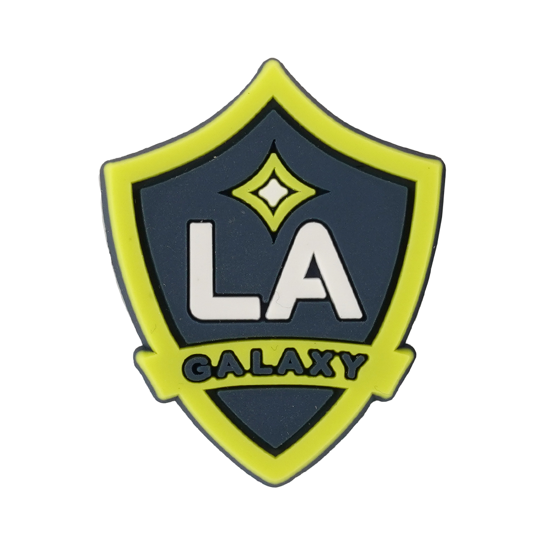 A shield-shaped rubber charm featuring the LA Galaxy soccer team logo in lime green, navy blue, and white.