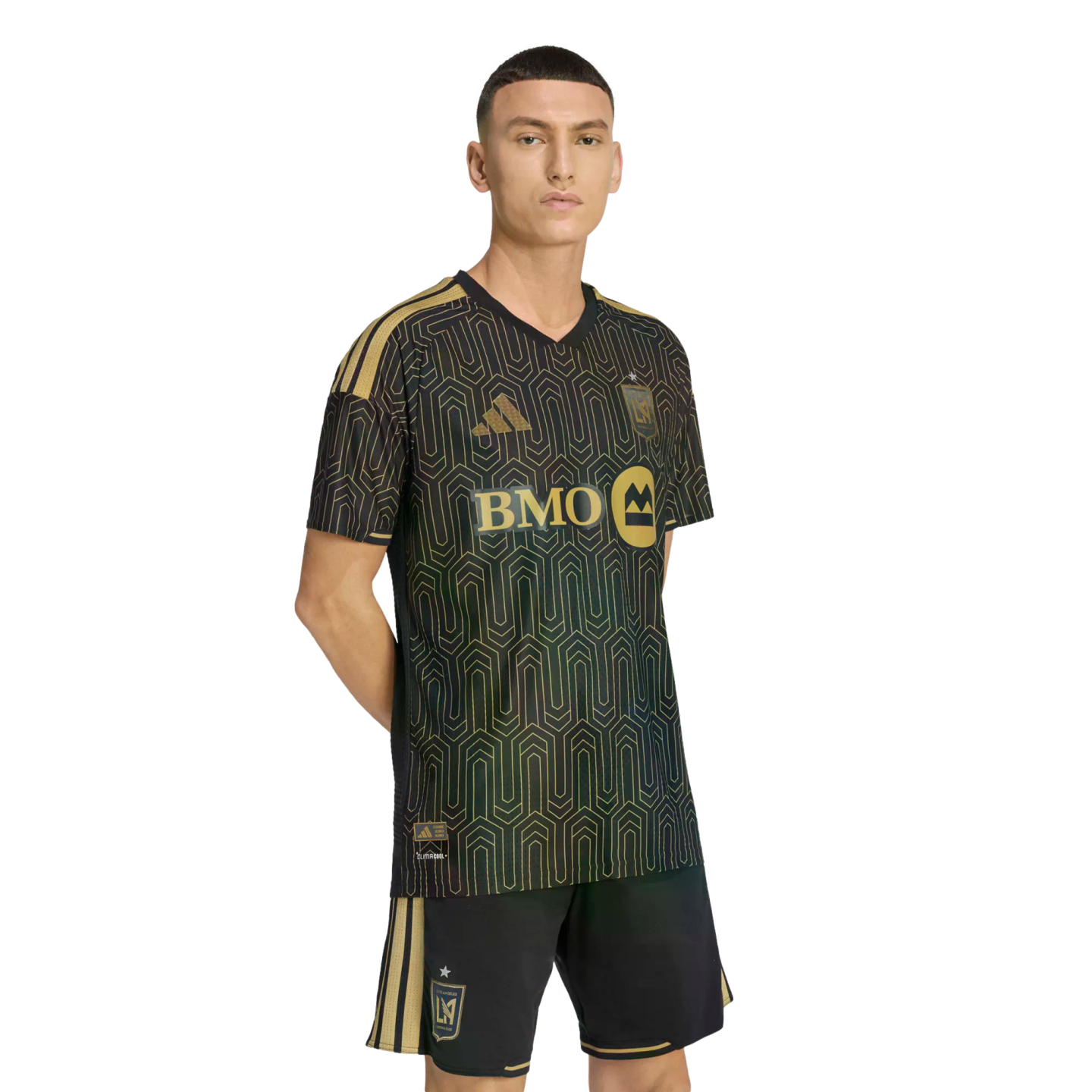A man wearing a black and gold LAFC soccer uniform with a geometric pattern and BMO sponsor logo, set against a solid black background.