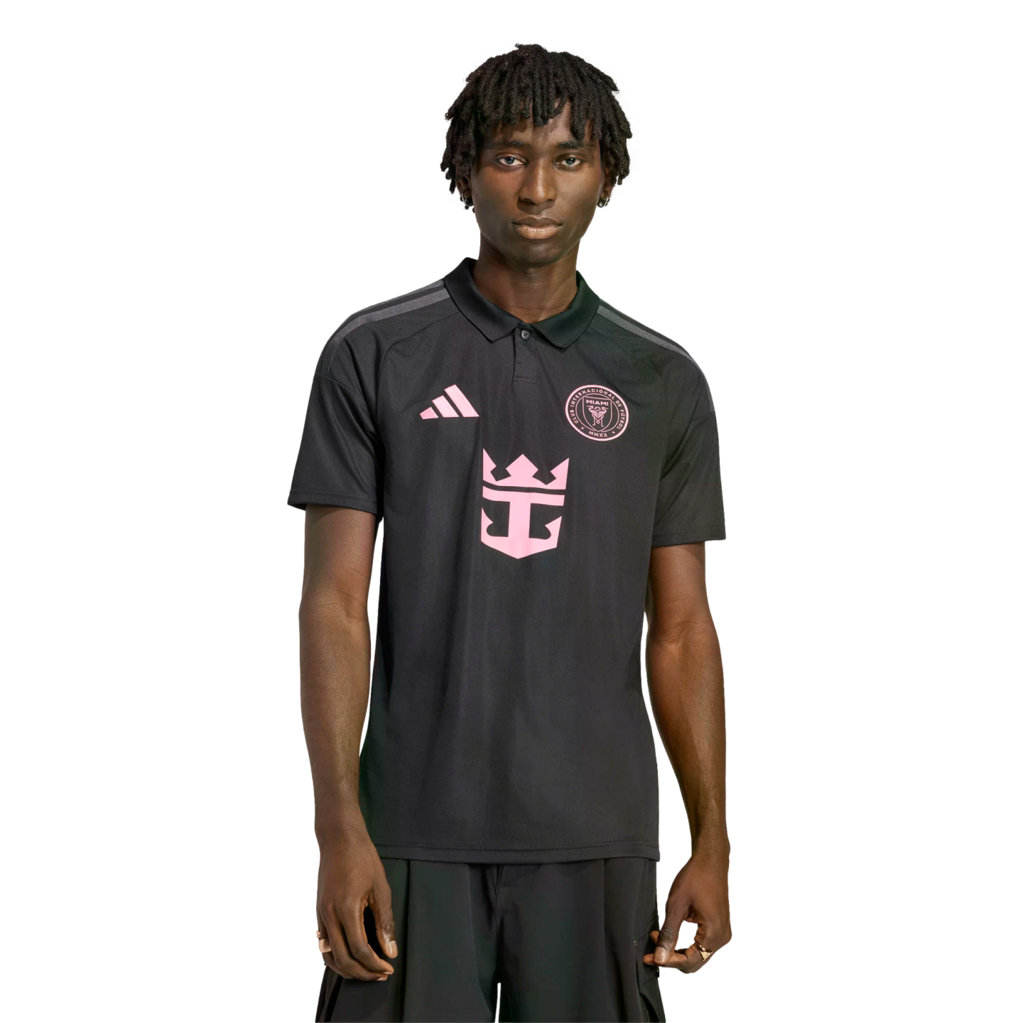 A man with dreadlocks wearing a black Inter Miami CF polo shirt with pink Adidas, team crest, and Royal Caribbean logos, isolated against a black background.