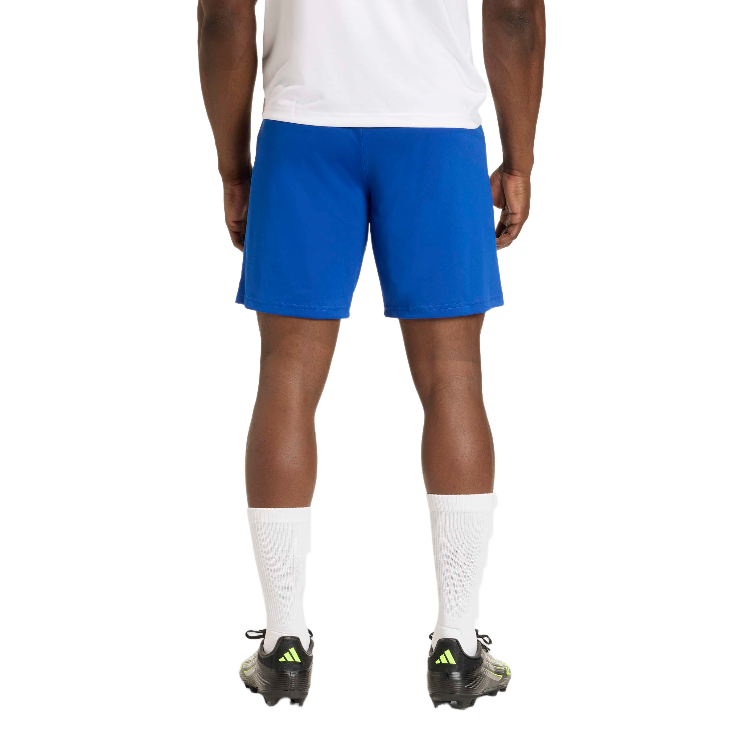 Rear view of a man wearing a white shirt, blue athletic shorts, white crew socks, and black soccer cleats.