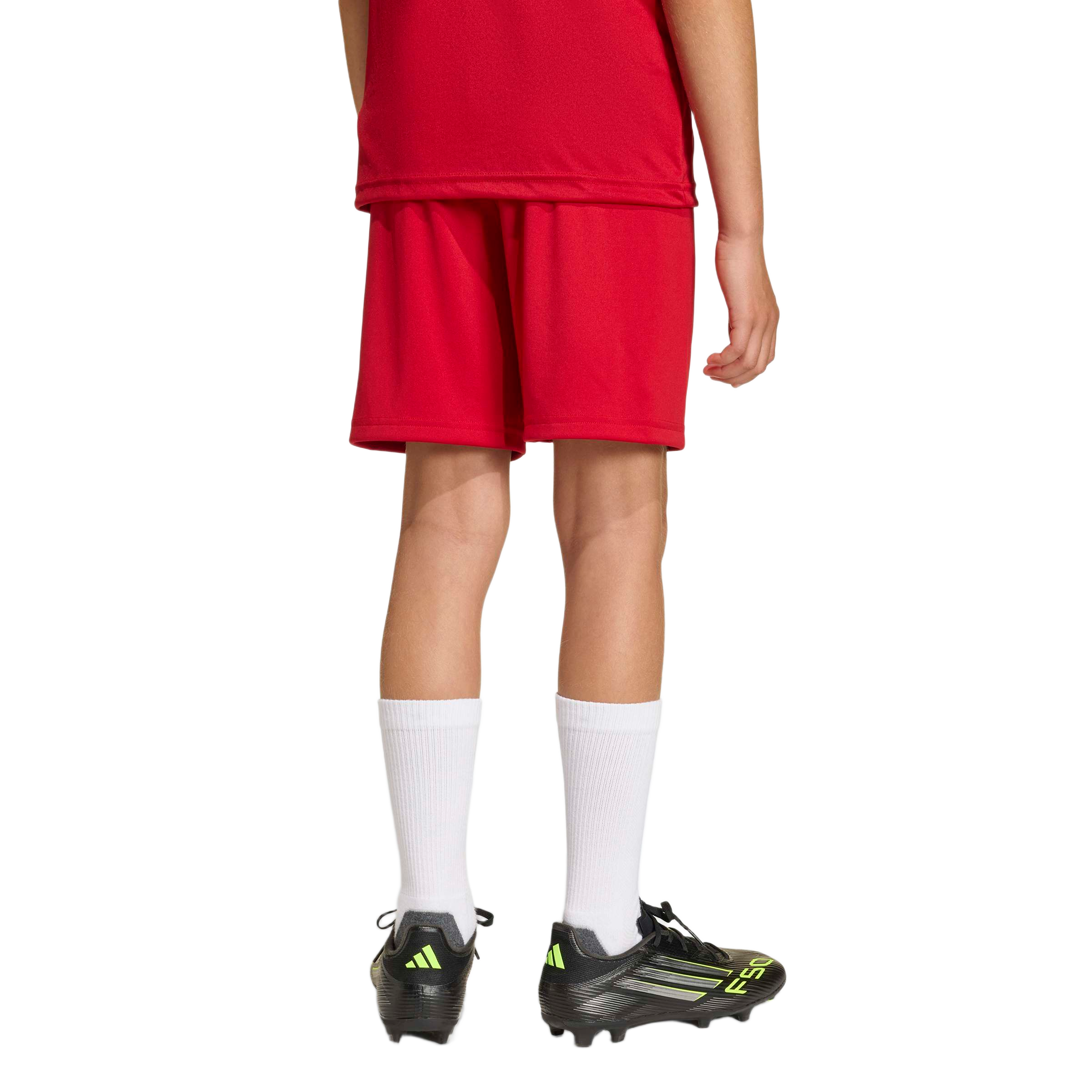 Rear view of a person wearing a red football kit, white crew socks, and black Adidas football boots with lime green details.