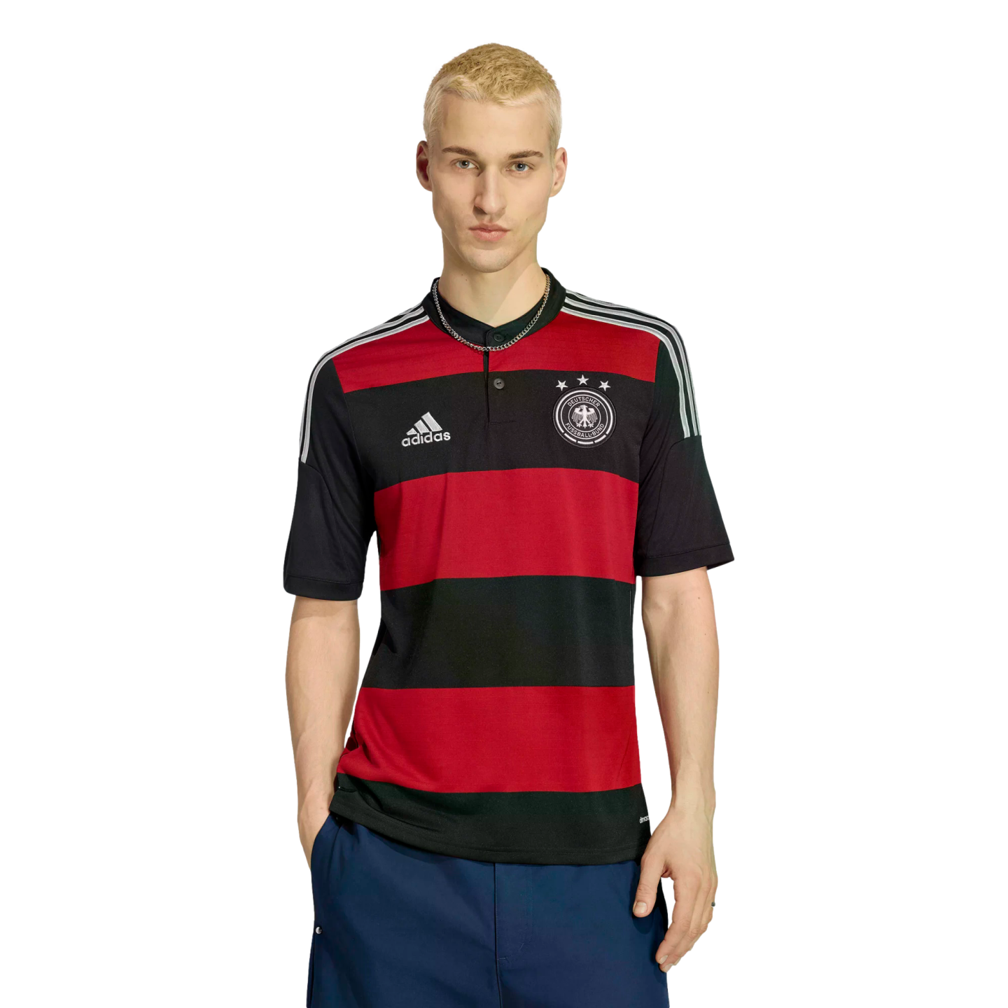 A young blonde man wears a red and black striped Adidas Germany jersey and dark blue shorts, posing against a white background.