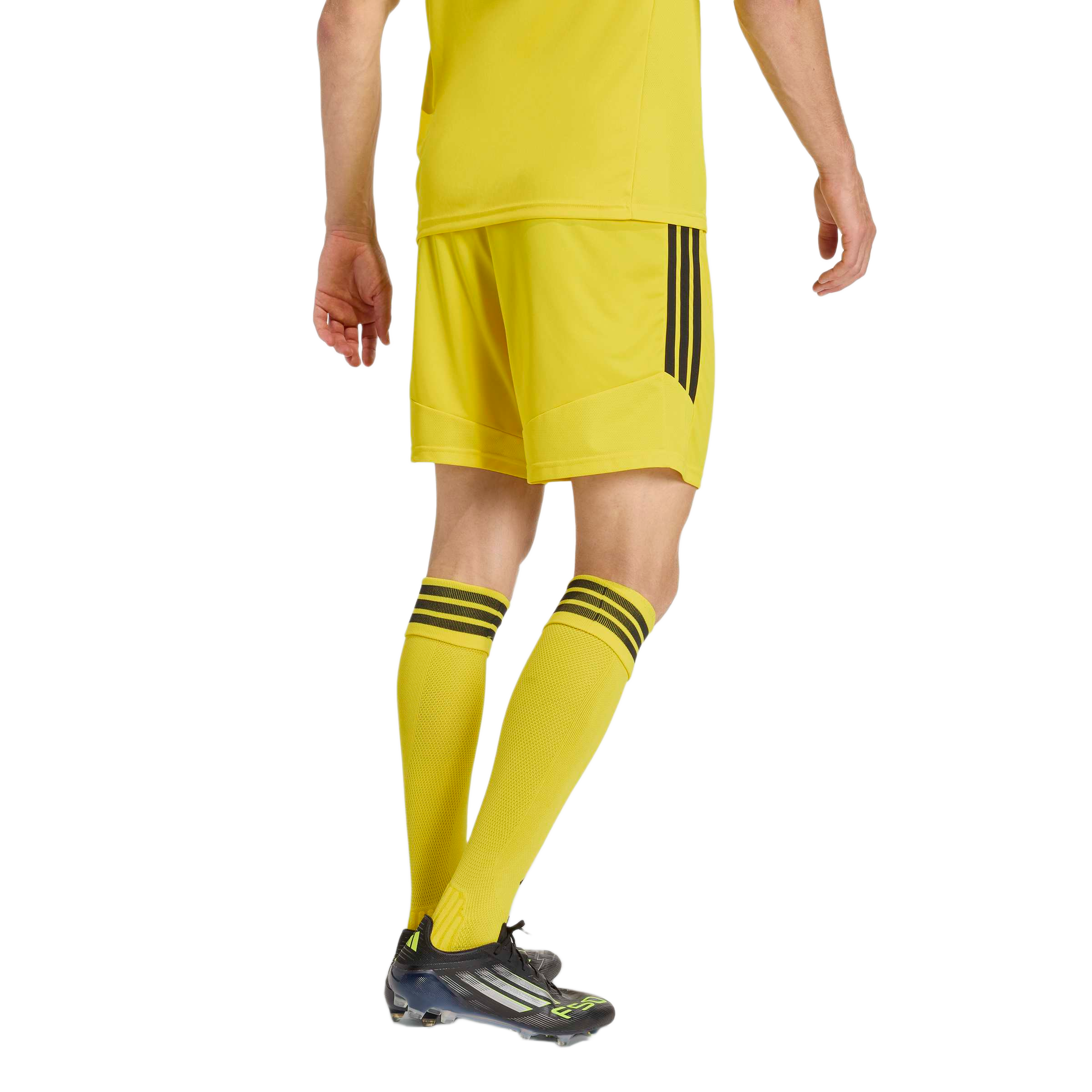 Rear view of a person wearing a yellow soccer kit with black stripes and black soccer cleats.
