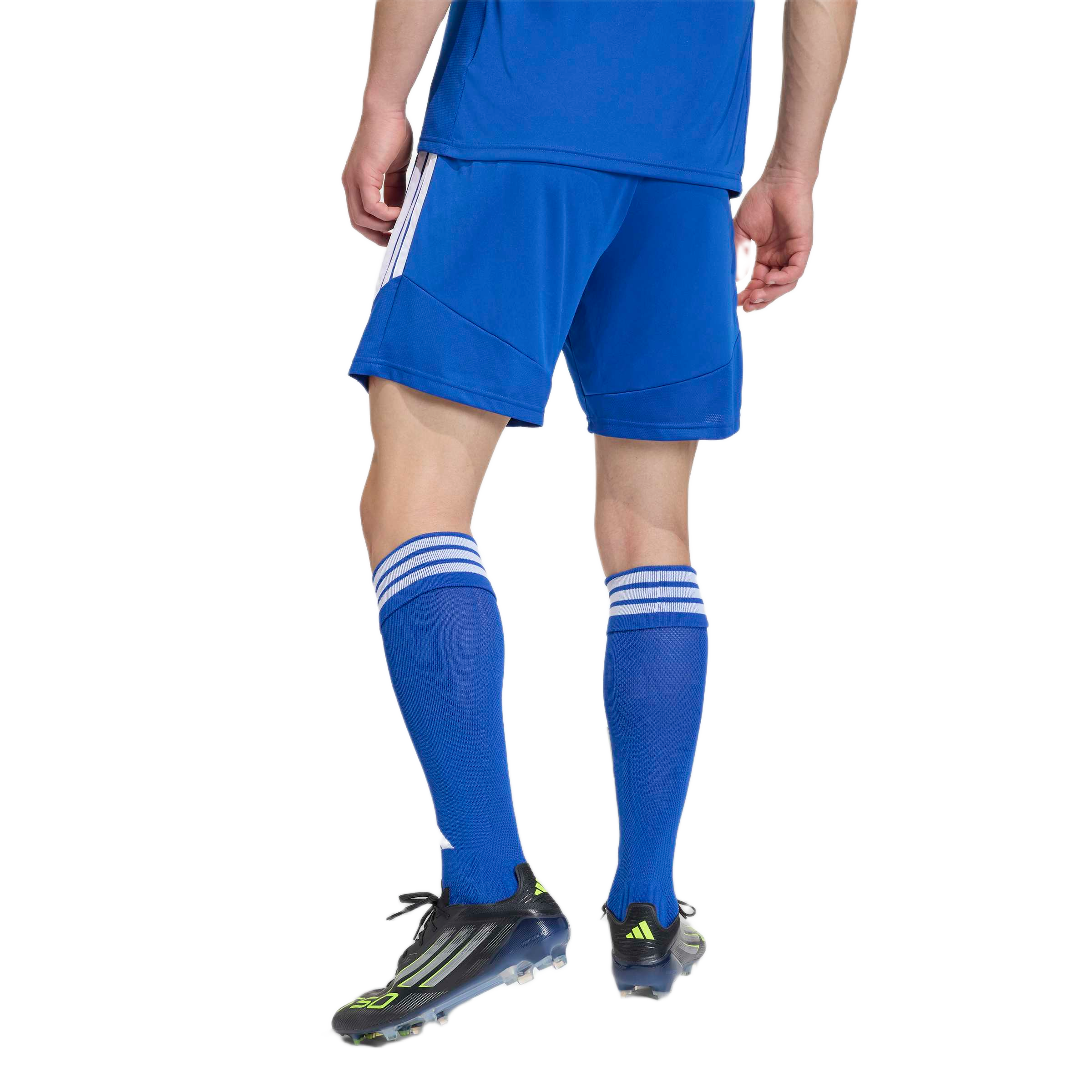 Rear view of a man wearing a blue soccer kit with matching socks and black and neon green cleats against a white background.