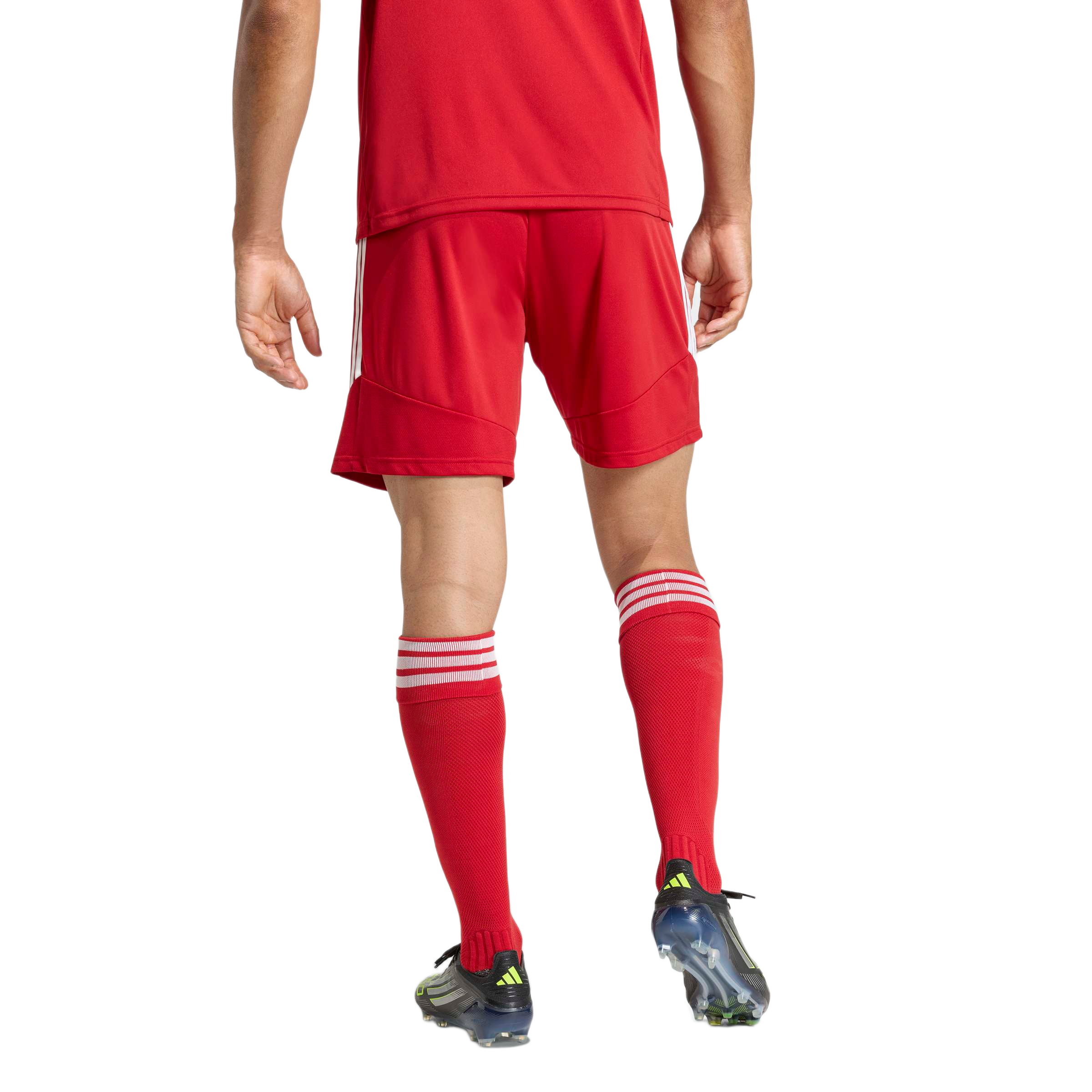 Rear view of an athlete in a red soccer kit with white-striped socks and black cleats against a plain background.