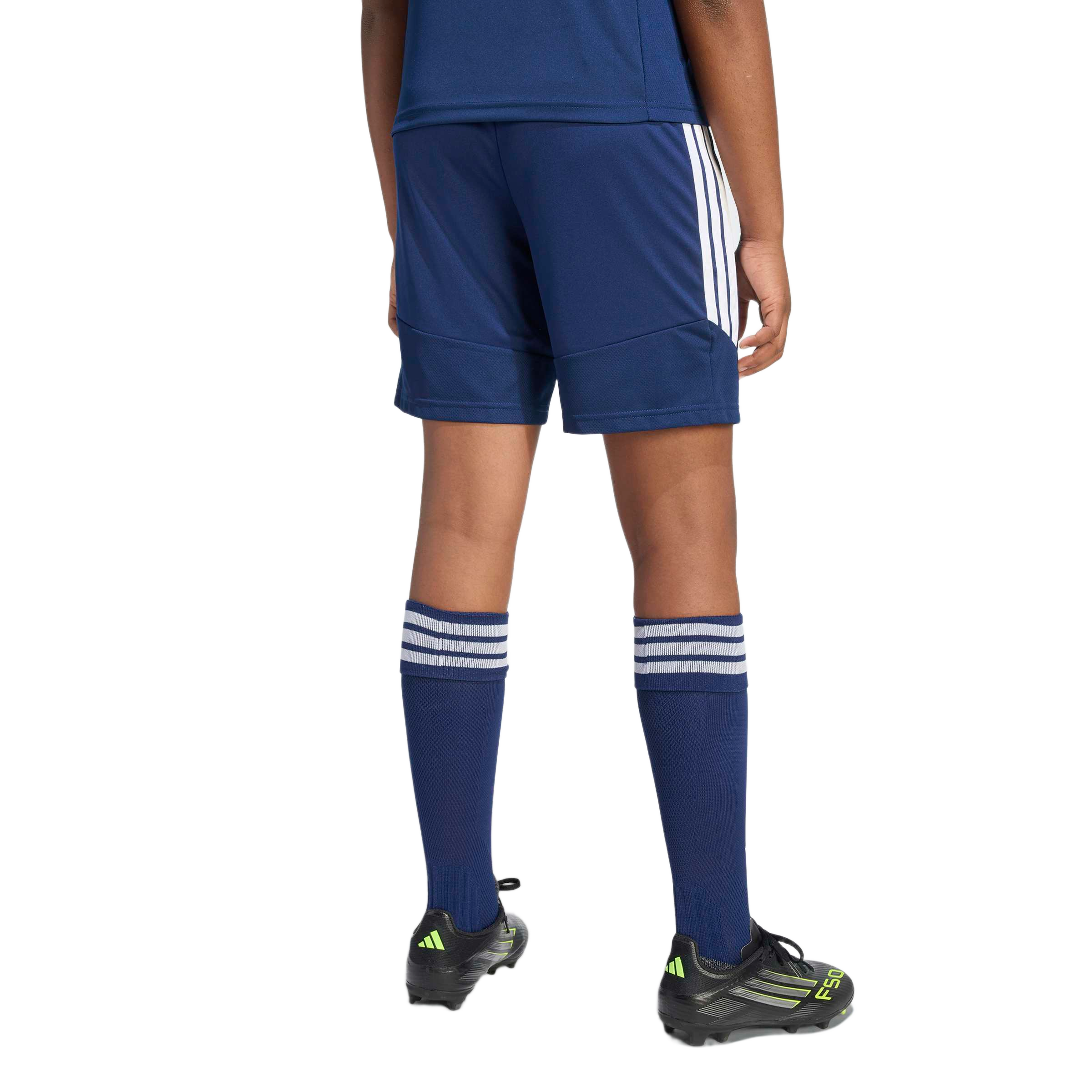 Rear view of a person wearing a navy blue soccer kit with white stripes and black cleats, standing against a light gray background.