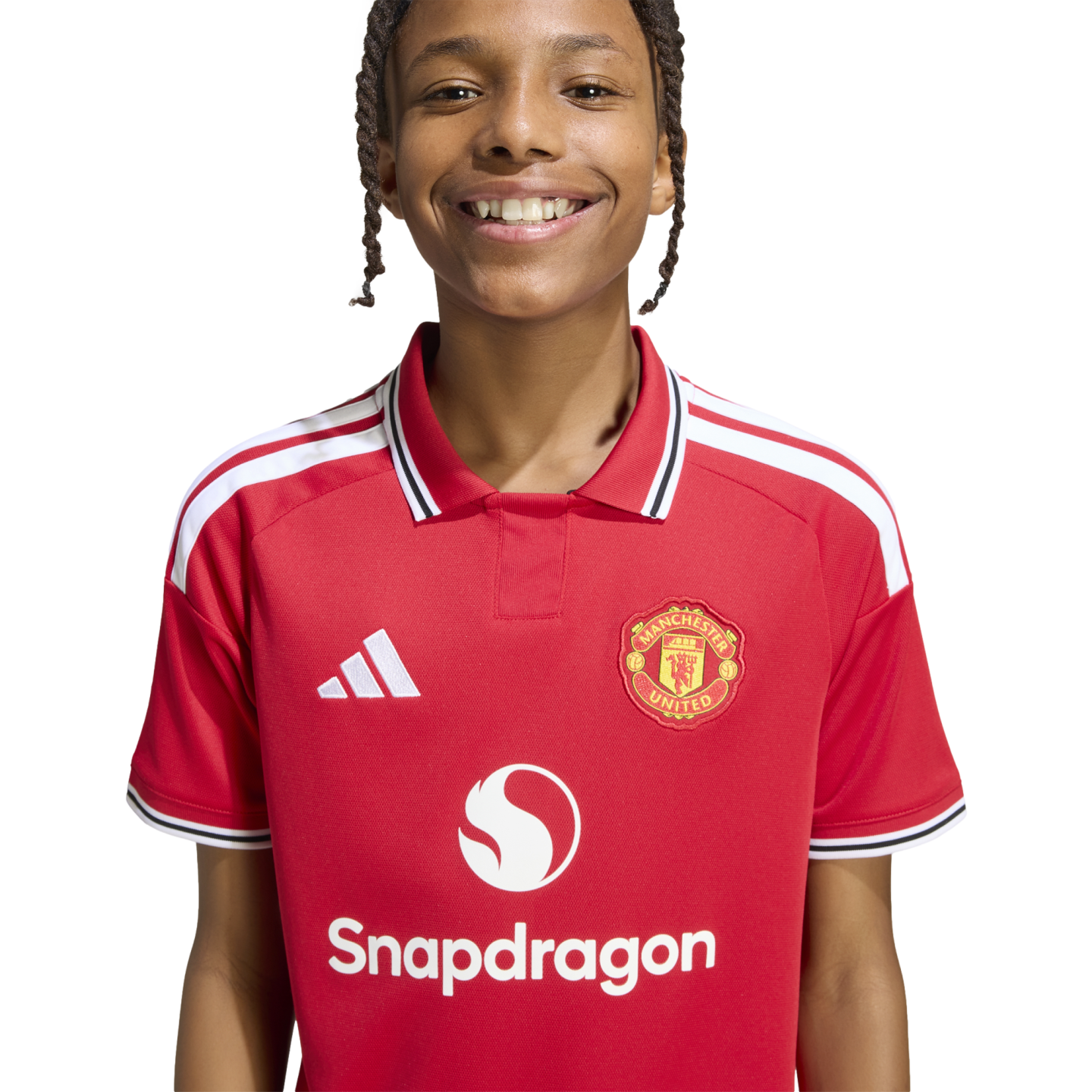 A smiling young person with braided hair wears a red Manchester United football shirt featuring the Snapdragon sponsor logo, set against a white background.