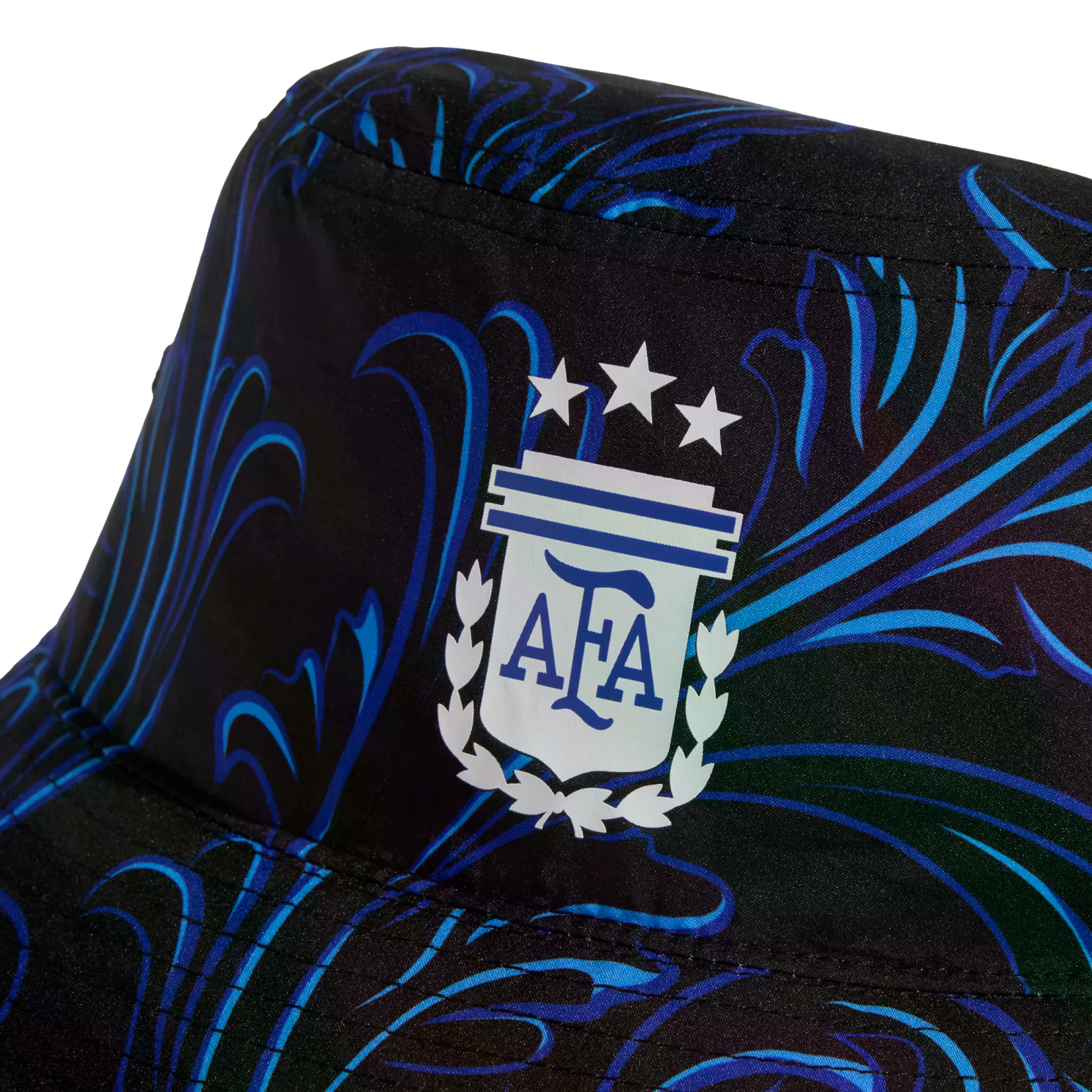 Close-up of a black bucket hat with a blue swirled pattern and the white and blue Argentine Football Association (AFA) crest with three stars.
