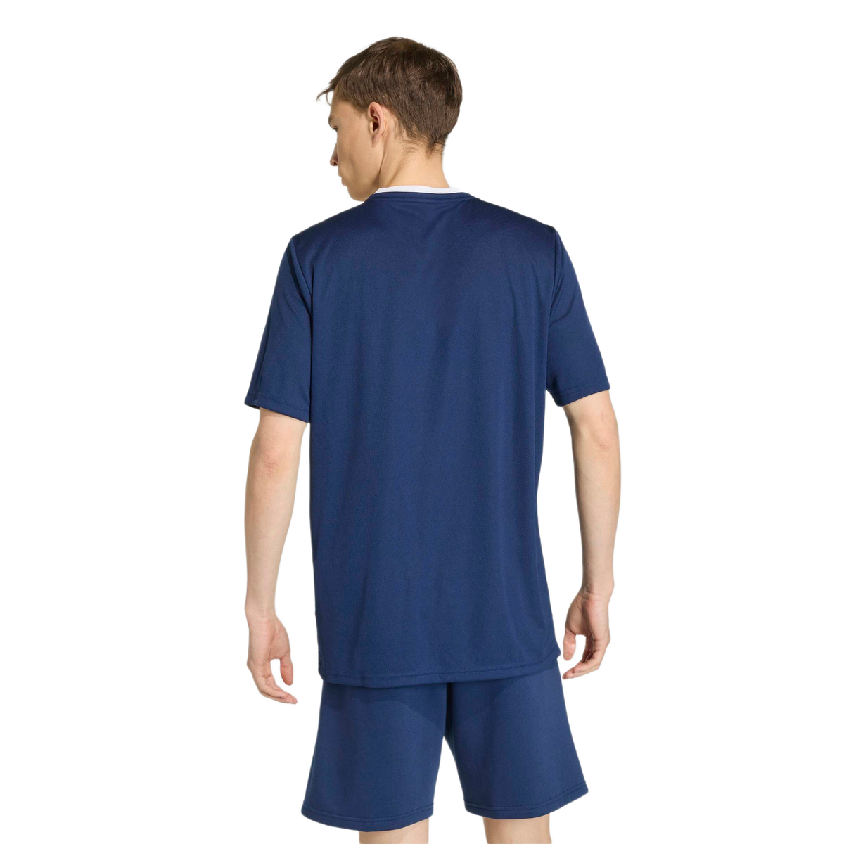 Rear view of a man wearing a navy blue athletic t-shirt and matching shorts against a light background.