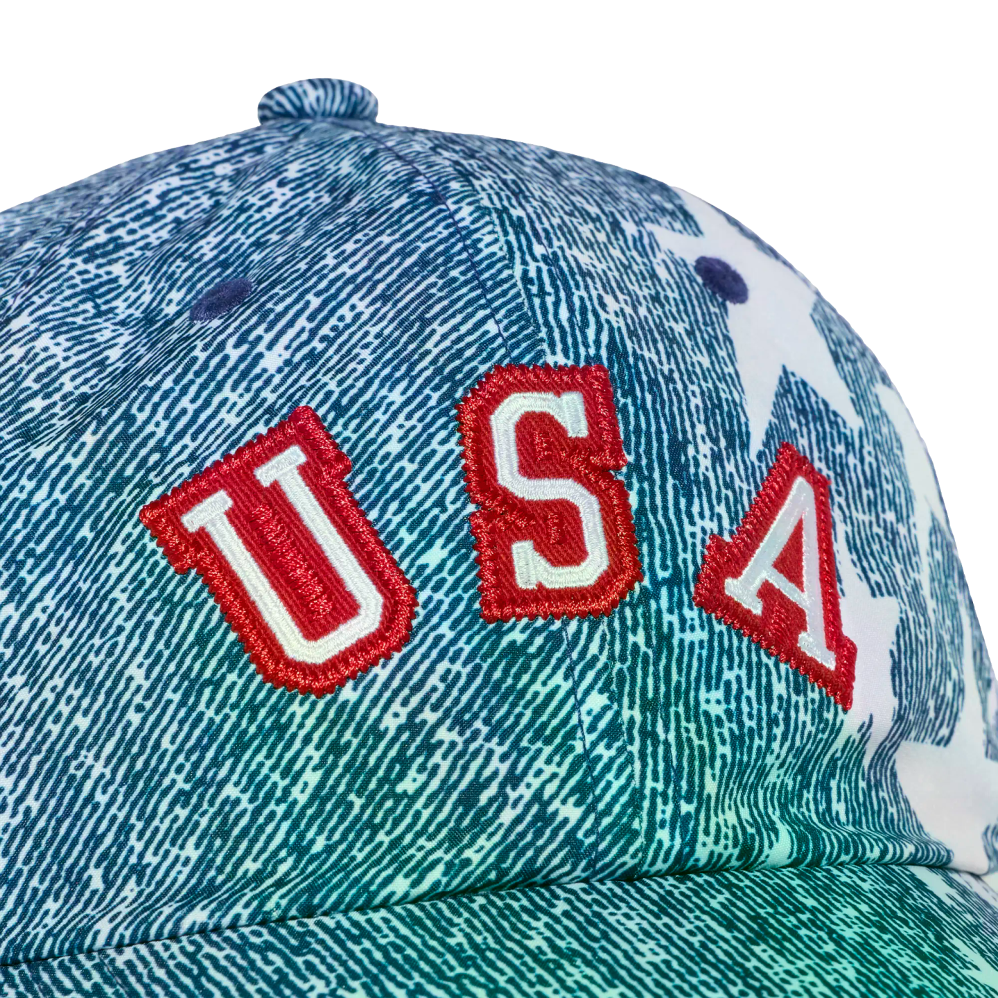 Close-up of a baseball cap with a blue-green textured pattern, featuring large red and white embroidered "USA" letters on the front against a black background.