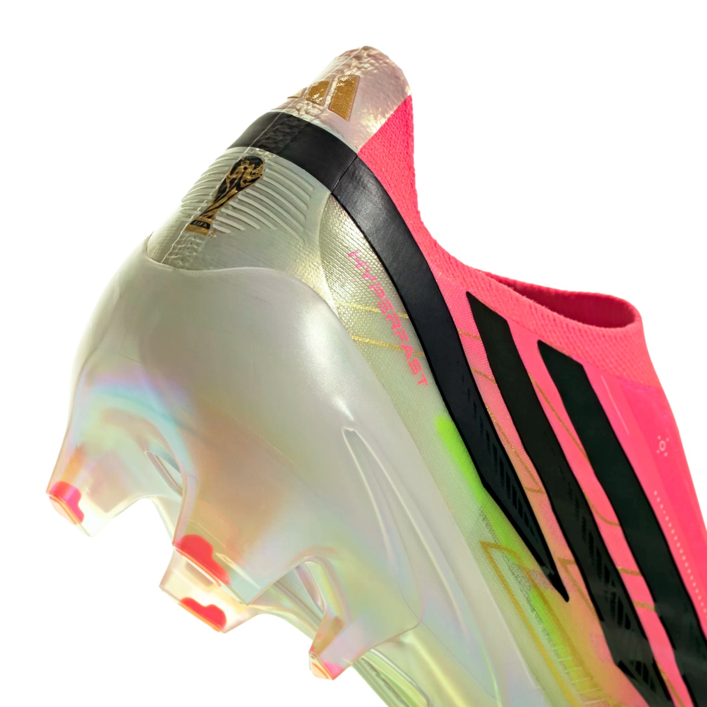 Close-up of an iridescent Adidas soccer cleat with pink and black accents. Features a gold FIFA World Cup logo on the heel and pink-tipped studs on an iridescent soleplate.