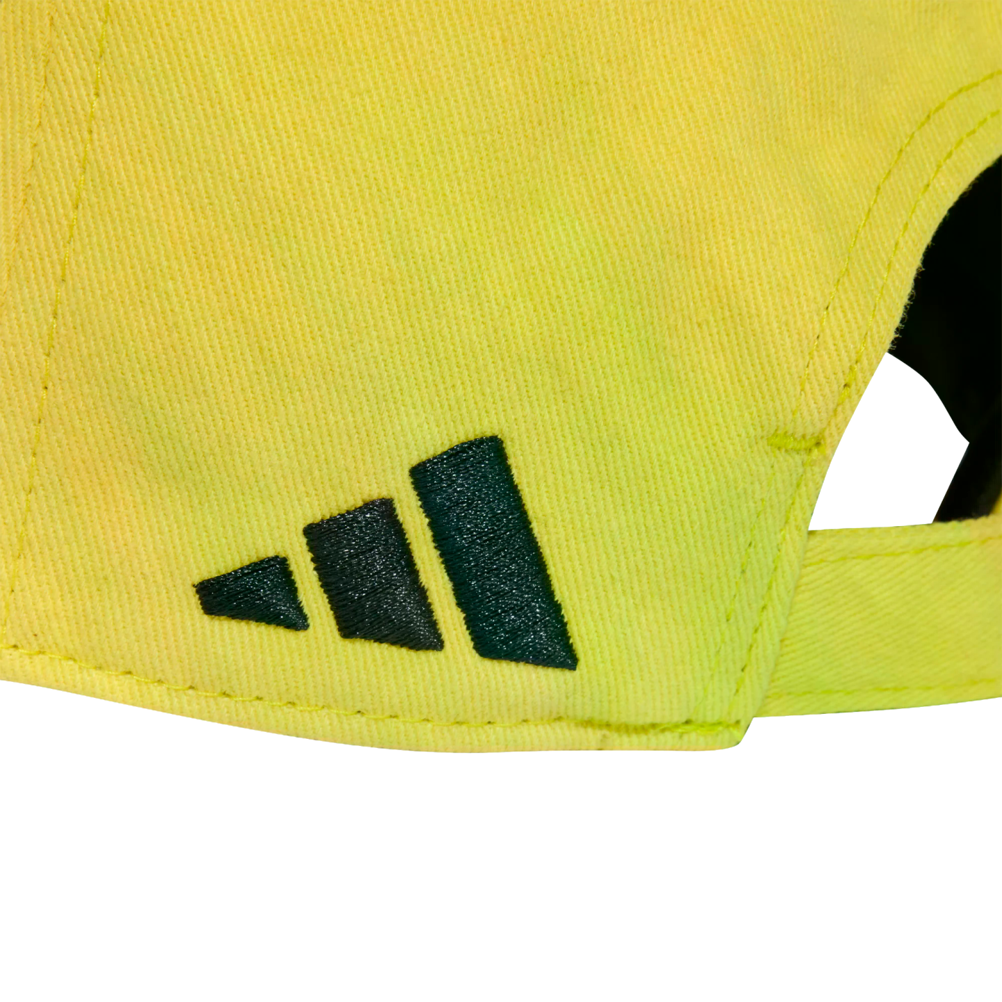 Close-up of the back of a bright yellow cap with the dark green Adidas mountain logo embroidered on the side.