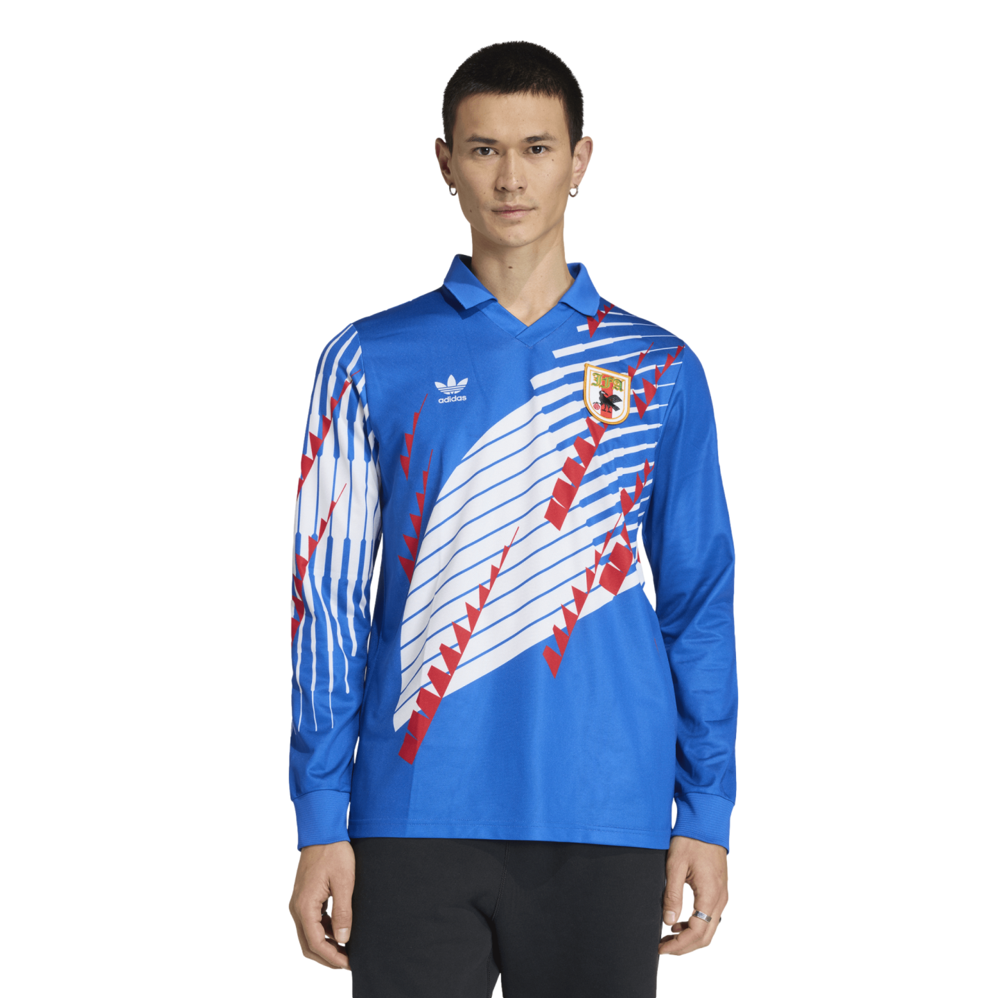 A male model wearing a long-sleeved blue Adidas soccer jersey with white stripes, red graphic accents, and a team crest.