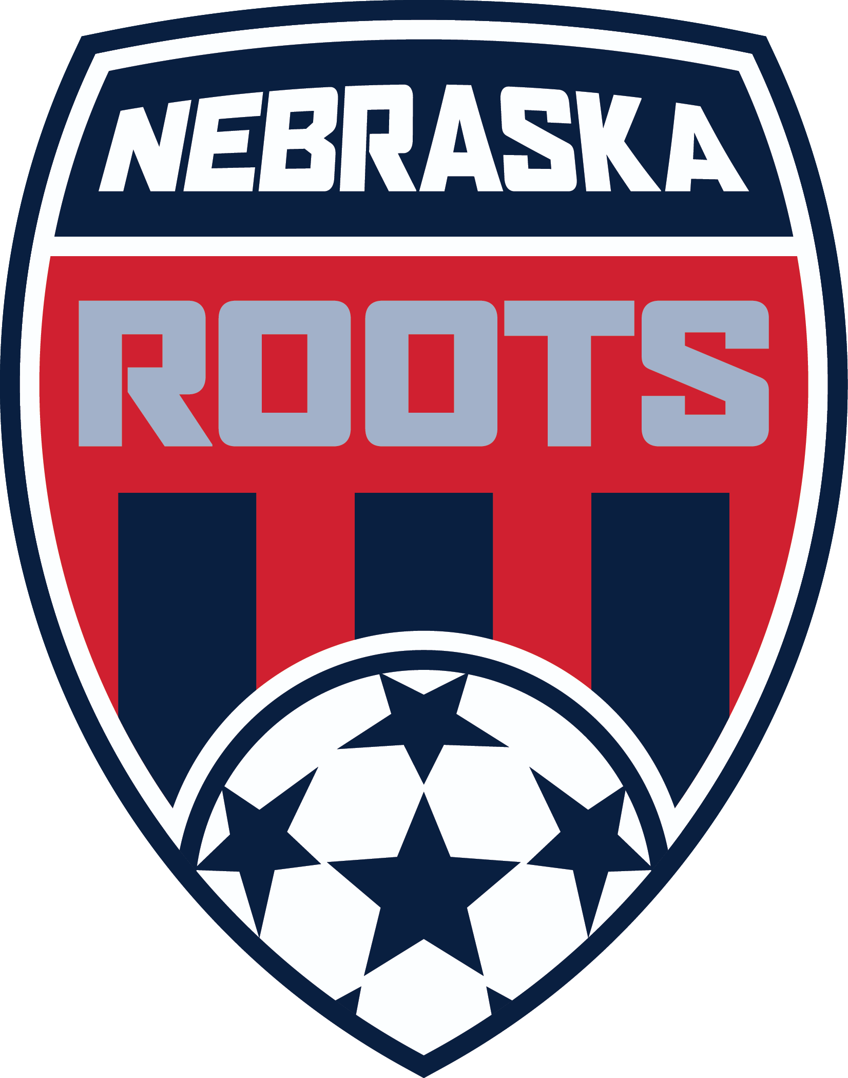 Shield-shaped Nebraska Roots soccer logo featuring white and gray text on a red and blue crest with vertical stripes and a star-patterned soccer ball at the bottom.