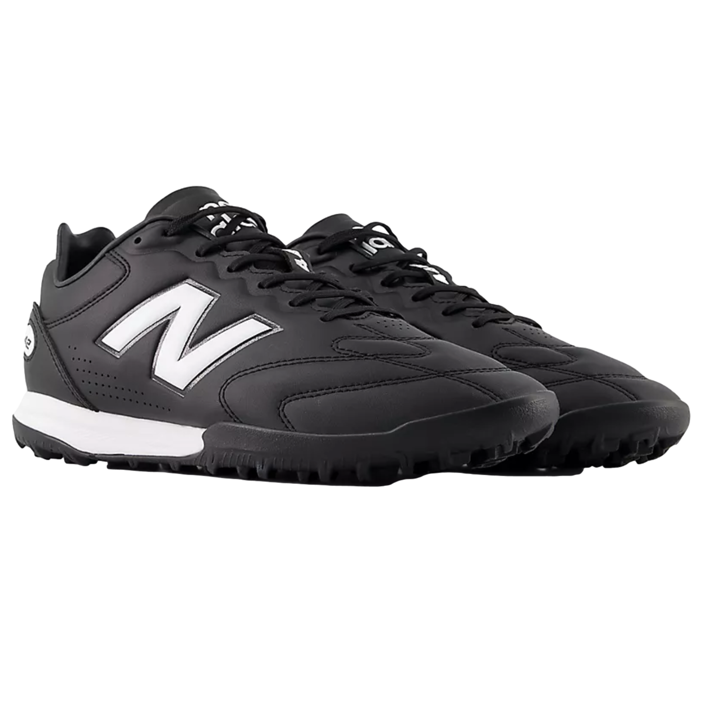 Pair of black New Balance soccer turf shoes featuring a white "N" logo and midsole, shown from a side angle against a black background.