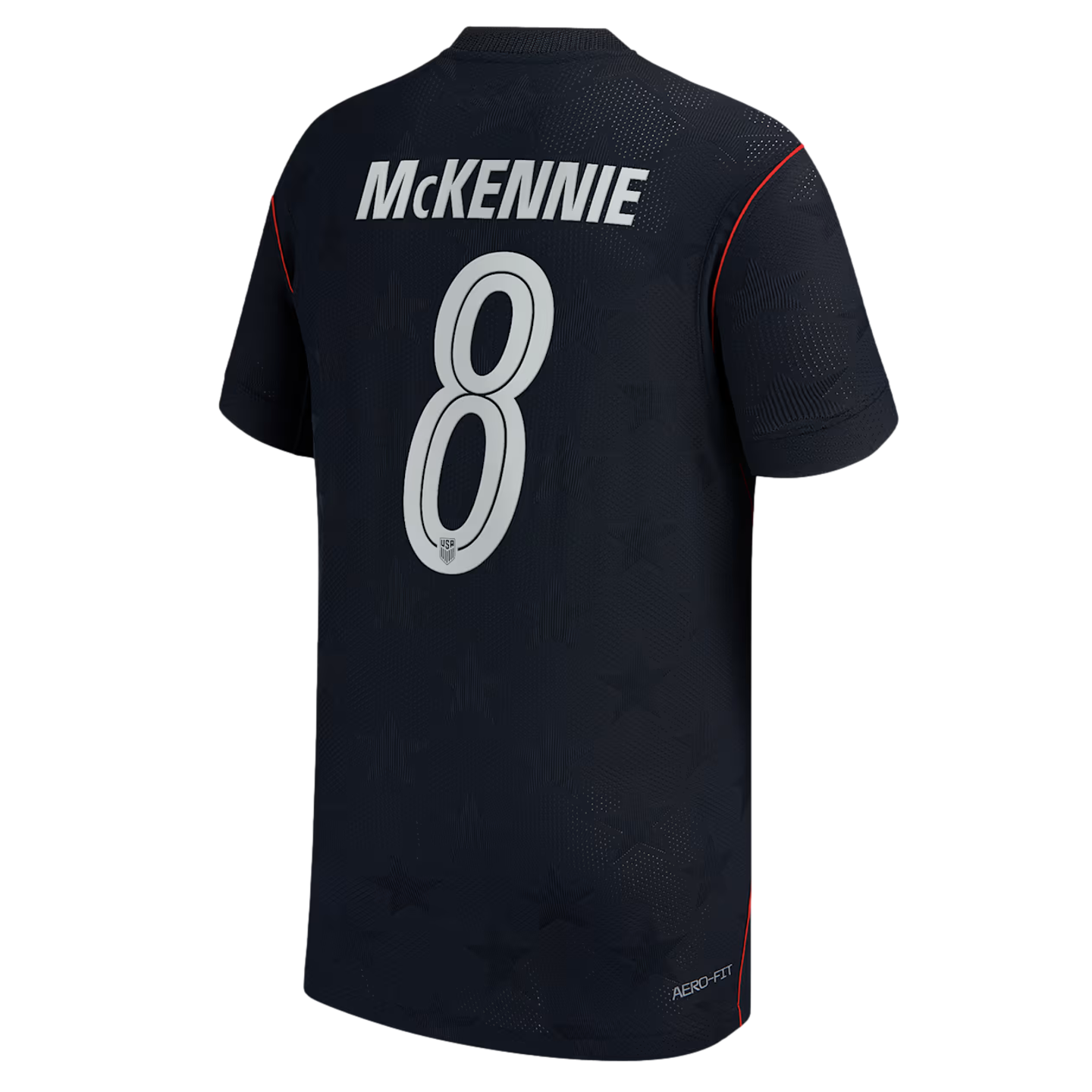 Back view of a navy blue USMNT soccer jersey featuring "MCKENNIE" and the number 8 in white. The jersey has red trim and a subtle tonal star pattern.